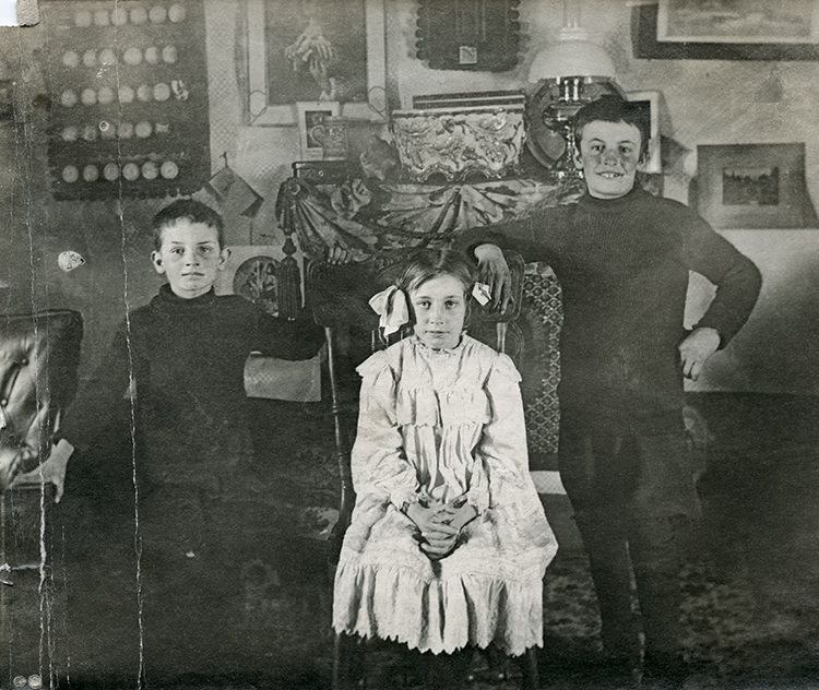 Photo en noir et blanc représentant Jacques, Marie-Antoinette et Marcel Castelein dans une maison, en 1911.