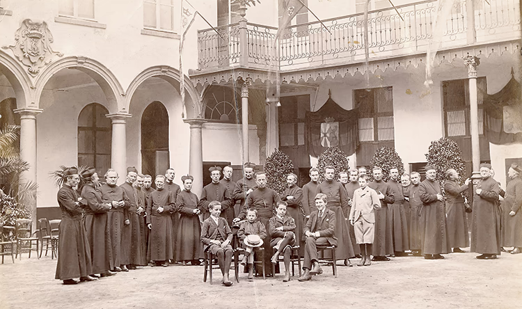 Photo en noir et blanc d’un groupe d’élèves et d’enseignants religieux dans la cour intérieure du Collège Saint-Michel de Bruxelles en 1892.