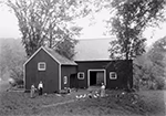 Grange en bois avec toit à deux versants, entourée d’arbres, et basse-cour avec poules devant, scène rurale à Newfane (Vermont) vers 1901.