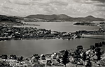 Vue panoramique du lac Memphrémagog depuis Newport (Vermont) en 1909, montrant le lac entouré de collines, des îles au centre et un village avec maisons en bois au premier plan.