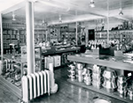 Intérieur d’une ferronnerie vers 1940 à Chicoutimi, avec rayons remplis de boîtes métalliques, étagères de produits variés et présentoirs de casseroles et ustensiles.