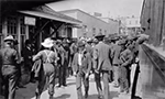 Photo en noir et blanc d’un groupe d'hommes se tenant devant une gare de Cobalt en Ontario, en 1906.
