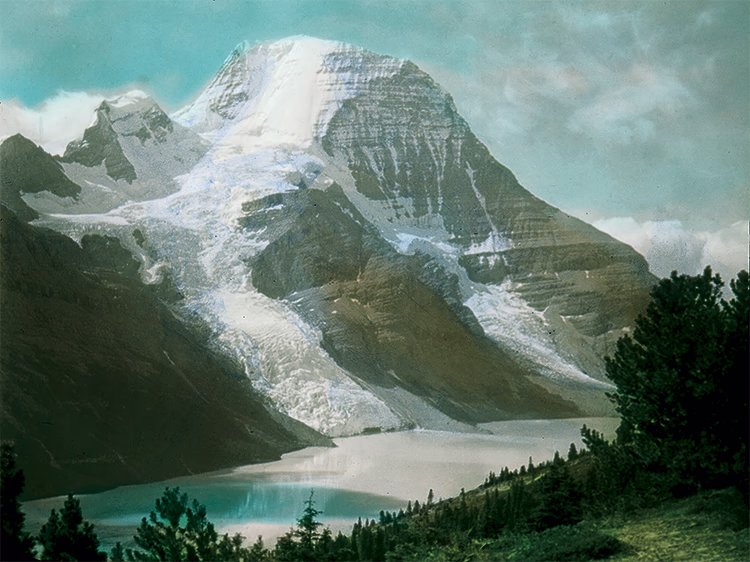 Image représentant le Mont Robson, couvert de neige, avec le lac Berg en avant-plan, vers 1930.